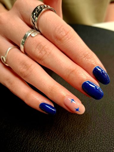 Hand with long blue nails, one featuring a light design with small stars.